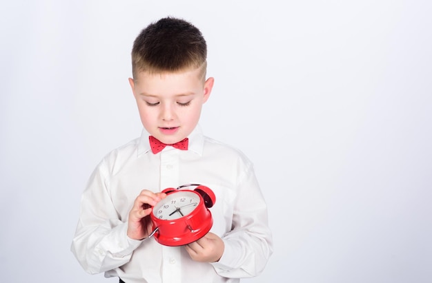 Time management Morning little boy with alarm clock Time to relax tuxedo kid Happy childhood happy child with retro clock in tie Party time Businessman Formal wear copy space Billionaire