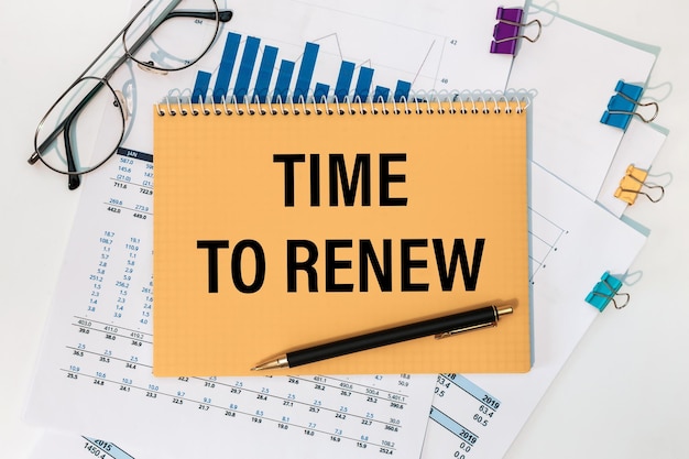 TIME TO RENEW is written on a notepad on an office desk with office accessories