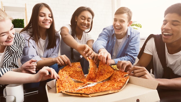 Time for snack Happy students eating pizza and chatting