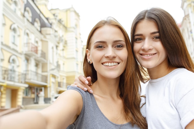 Time to take a picture Horizontal shot of two beautiful female friends taking a selfie smiling to the camera happily