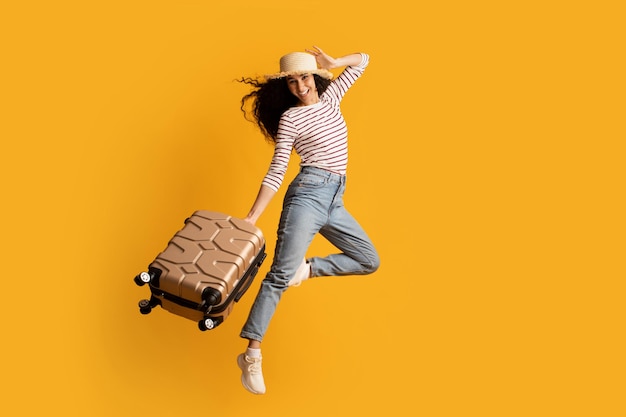 Time To Travel Cheerful Young Woman Wearing Wicker Hat Jumping With Suitcase