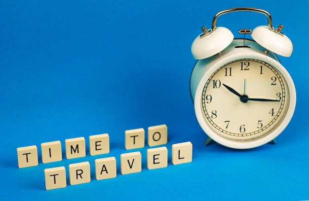 Time to travel slogan, trip concept 2021, composition on isolated blue backhround with alarm clock, copy space photo