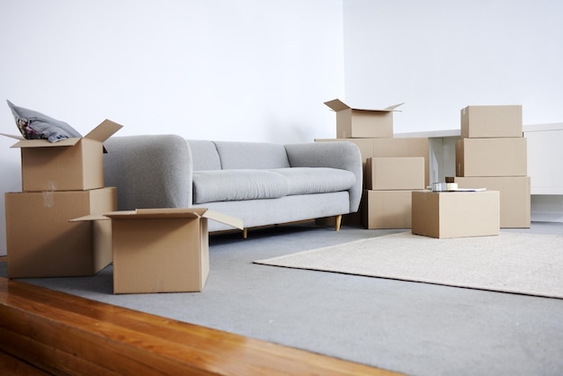 Time to unpack. Shot of cardboard boxes and a sofa in an empty living room during the day.