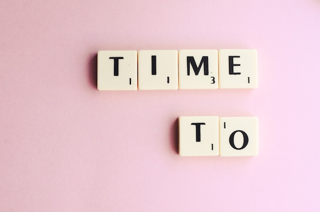 TIME TO word on wooden cubes on a pink background