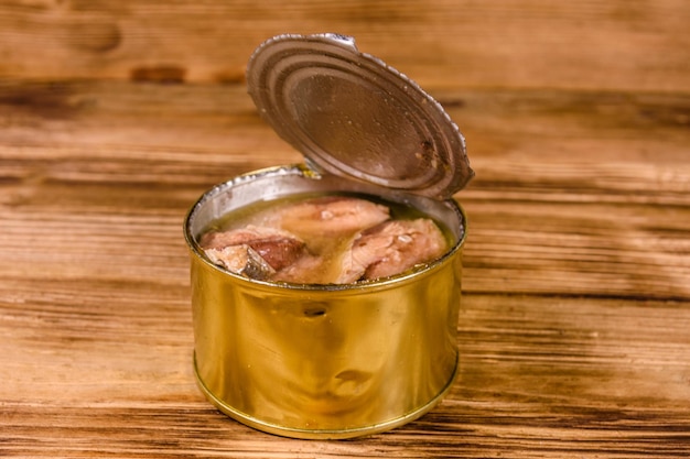 Tin can with sardine on wooden table