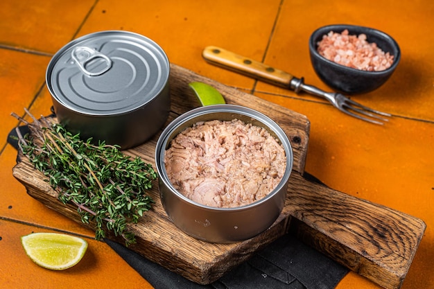 Photo tin with canned tuna fillet meat in olive orange background top view