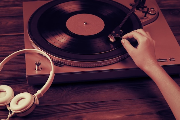 A tinted image of a hand placing a vinyl disc on the player