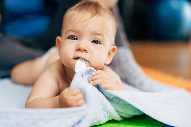 Tiny baby in diapers lies with his tummy on a blue blanket