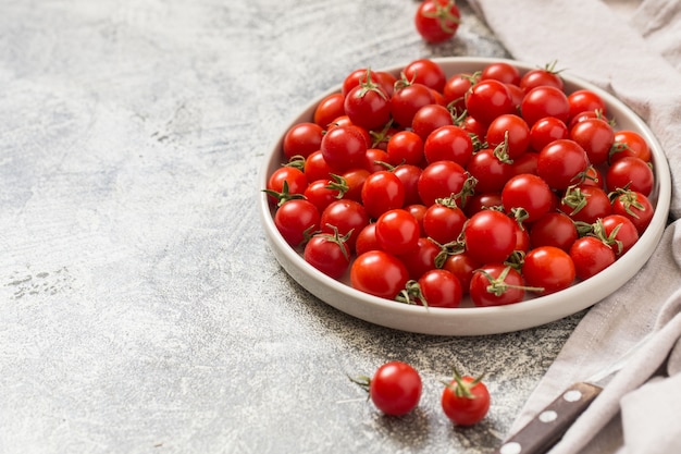 Tiny cherry tomatoes (ciliegini, pachino, cocktail). group of cherry tomatoes on a gray concrete  ripe and juicy cherry tomatoes