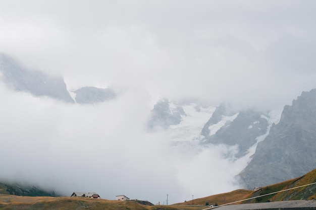 Tiny houses against huge glacier in mountains autumn landscape in French alps