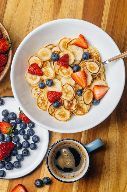 Tiny pancakes for breakfast. Pancakes with strawberries and blueberries cooked in the morning for breakfast in the home kitchen. 