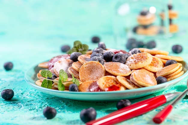 Tiny pancakes with fresh blueberries, mint and berry syrup