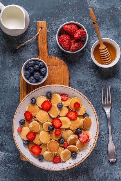 Tiny pancakes with strawberries and blueberries for breakfast