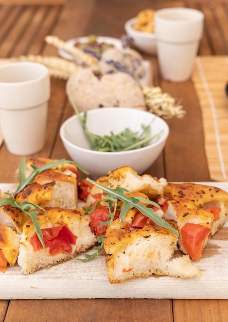 Tipical summer south Italian appetizer focaccia with cherry tomatoes and rucola served outdoor