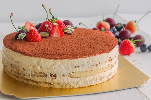 Tiramisu cake sprinkle with cacao powder and decorated with fresh fruits. Italian classic 