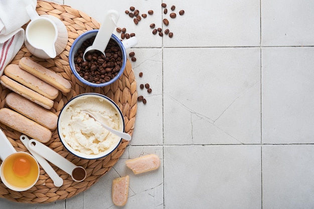 Tiramisu dessert Ingredients for making dessert tiramisu Cooking Italian food dessert Tiramisu with all necessary ingredients cocoa coffee mascarpone cheese on grey stone background Copy space