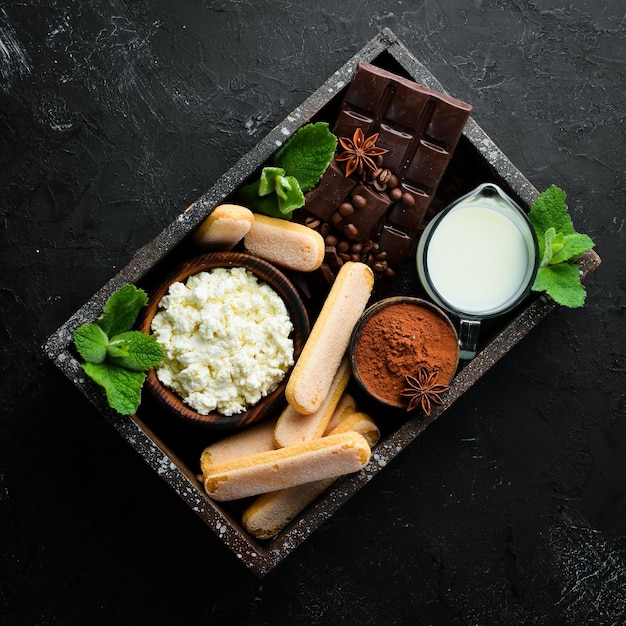 Tiramisu dessert Ingredients for tiramisu preparation Top view On a black stone background Free space for your text