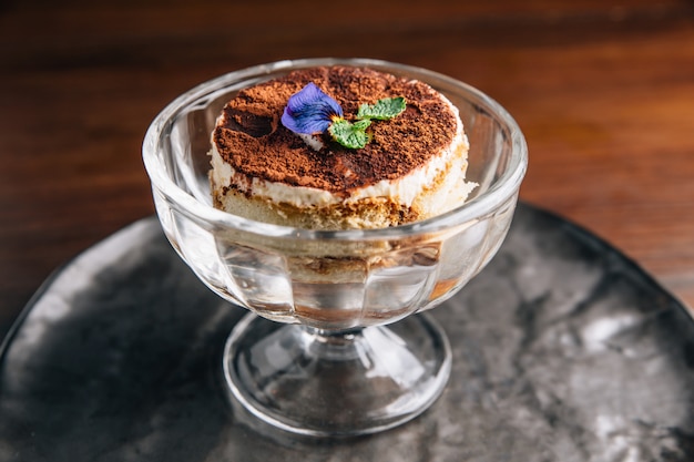 Photo tiramisu in glass cup is a coffee-flavoured italian dessert. it is made of ladyfingers dipped in coffee.