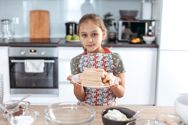 Tiramisu making process in the kitchen little girl making Italian desert with cocoa and espressodipped ladyfingers with mascarpone cream step by step 1