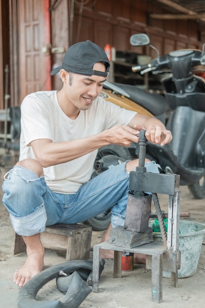 Tire patcher holds the press before patching the leaky inner tube in a motorcycle repair shop