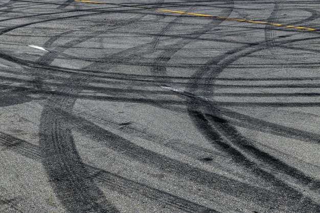 Tire track mark on asphalt tarmac road race track texture and background Abstract background black tire tracks skid on asphalt road in racing circuit Tire mark skid mark on asphalt road