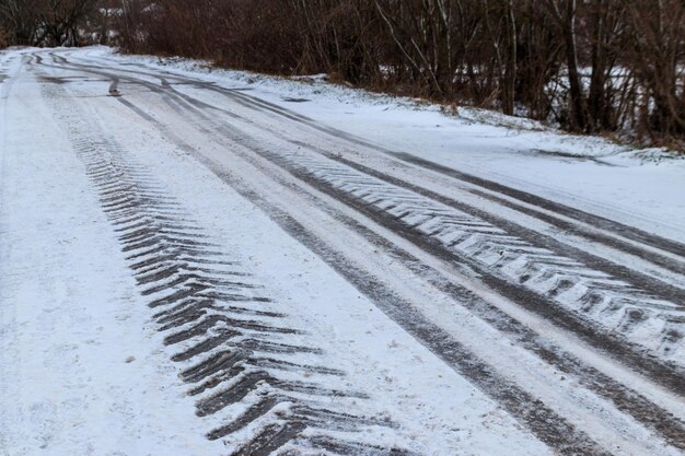 Photo tire tracks on icy road covered with snow