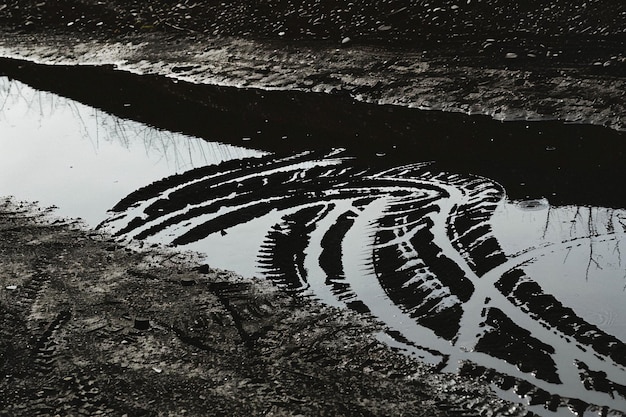 Photo tire tracks reflected in puddle on dirt road