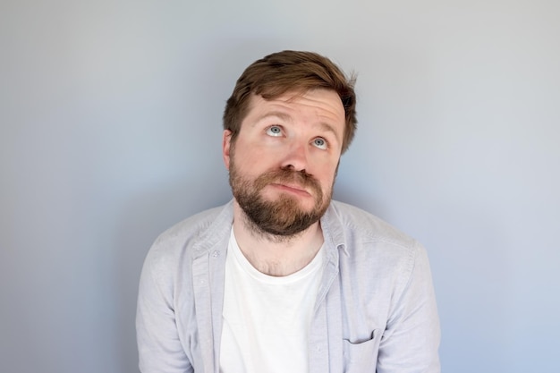 Tired bearded man in a shirt looks with his eyes upward with suffering and supplication