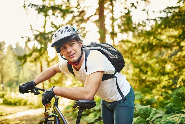 Tired bicyclist in sport clothes and helmet taking break after outdoors training Healthy caucasian man spending free time for workout on fresh air