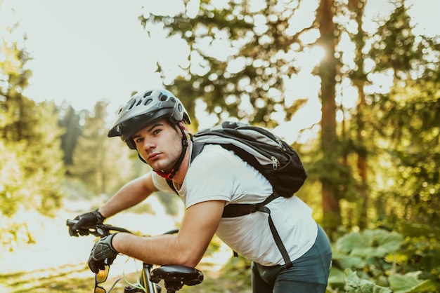 Tired bicyclist in sport clothes and helmet taking break after outdoors training Healthy caucasian man spending free time for workout on fresh air