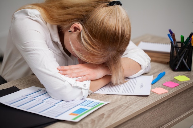 Tired business woman working with documents in the office at the desk