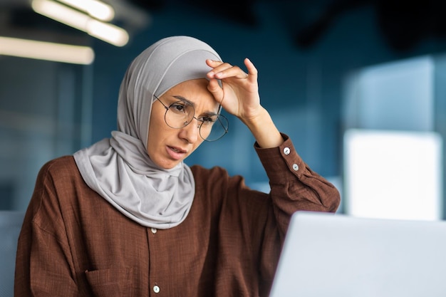 Tired business woman working at workplace inside office muslim woman with hijab is sick with severe