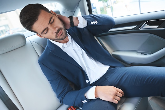 Tired businessman sitting in the car