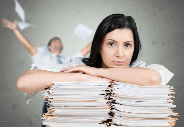 Tired businesswoman with stack of documents looking at camera