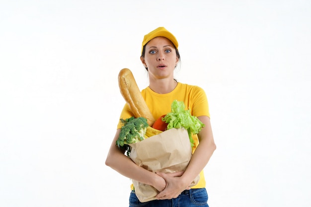 Tired delivery woman in yellow posing with grocery bag