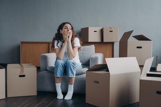 Tired divorced girl sitting with cardboard boxes on relocation day Moving to rented house eviction