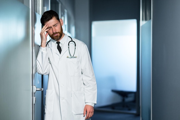 Tired doctor overworked at work has a severe headache feels bad a man in the corridor of the clinic is disappointed with the result