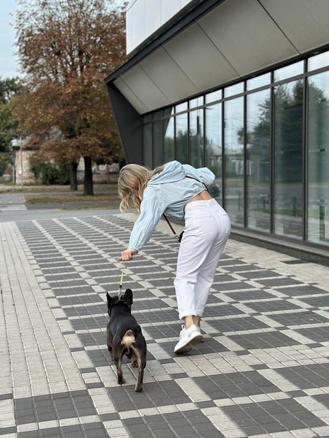 Photo a tired dog returns from a walk girl and dog on a leash rear view walking a warm autumn day