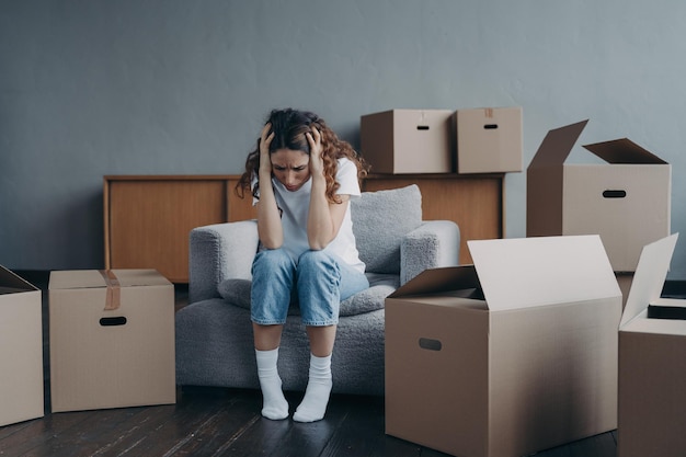 Tired european woman sitting among packed boxes Hopeless young lady getting in trouble