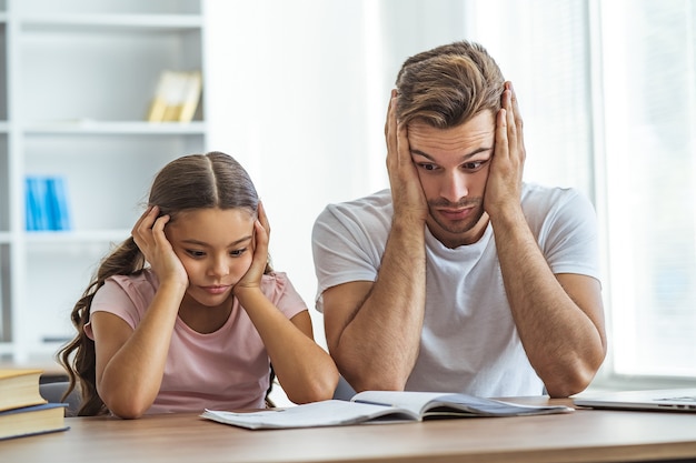 The tired father and a daughter doing homework at the desk