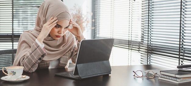 Tired frustrated young muslim business woman brown hijab feeling stressed holding head with hands, business problem failure concept