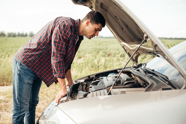 Tired man tries to repair a broken car