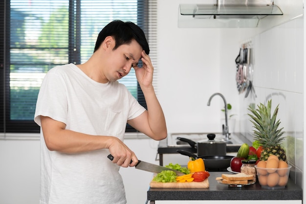 Tired man with preparing vegetables to cooking in kitchen at home