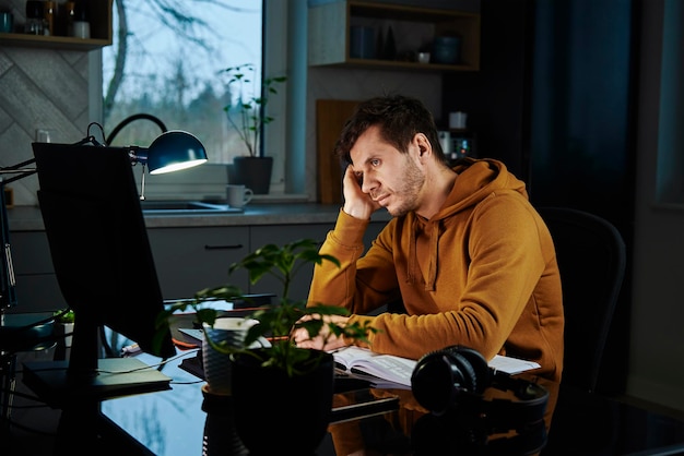 Tired man works late at workplace in the night