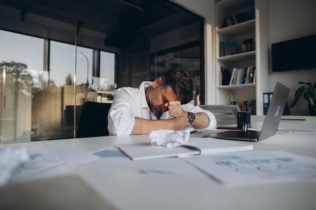 Tired manager alone in the office working overtimexA