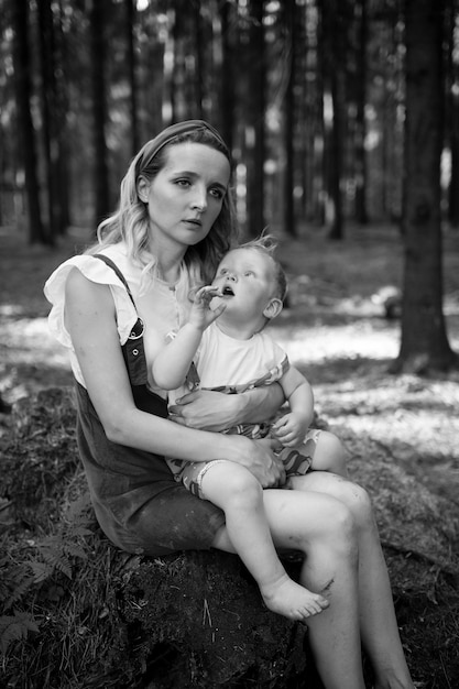 Tired mother posing with her funny son in the forest