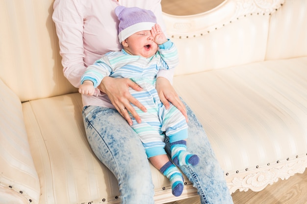 Tired newborn baby boy rubbing eyes