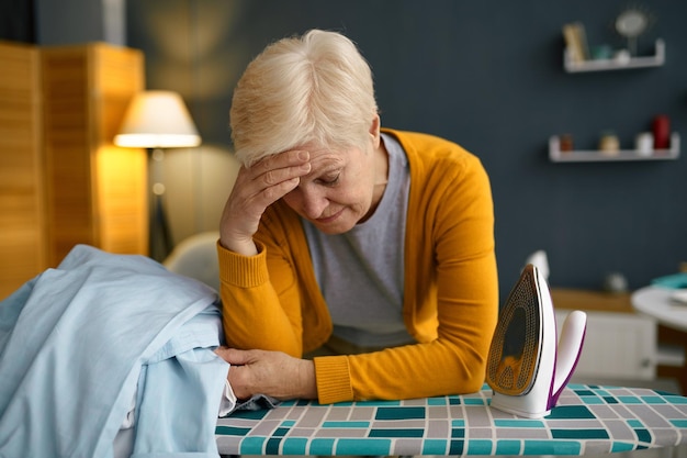 Tired old woman front of ironing board