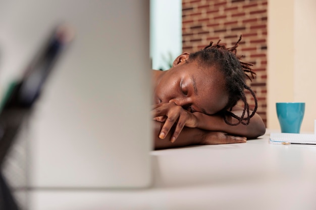 Tired overworked employee sleeping on desk at daytime, sleepy stressed remote worker, professional burnout. Student lying on desk, freelancer oversleeping at workplace, focus on face