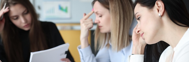 Tired and pensive businesswoman with documents and laptops at her work table. Challenging business tasks and goals concept